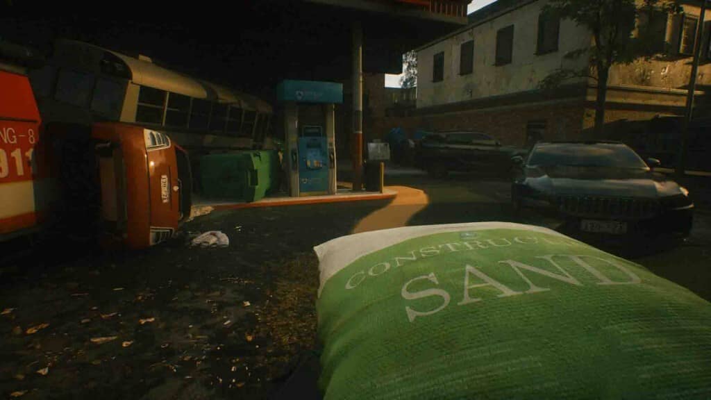 A Quiet Place The Road Ahead gameplay, túi cát chắn đường và ô tô cũ nát gần trạm xăng, gợi không khí hậu tận thế.