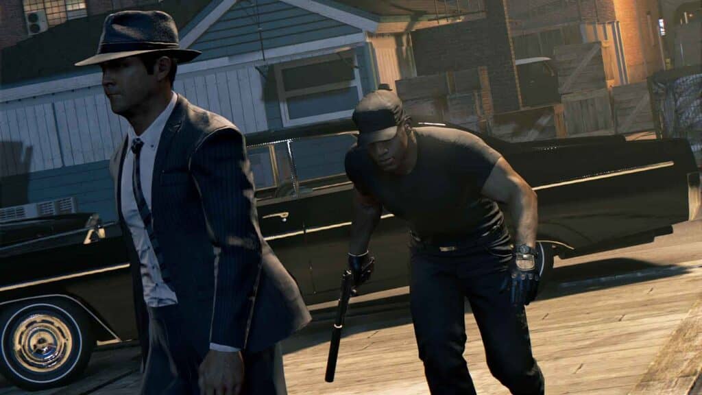Các nhân vật chính và bối cảnh thành phố của Mafia III Lincoln Clay và một thành viên băng đảng đang đi bộ, với xe hơi cổ điển phía sau trong Mafia III Definitive Edition
