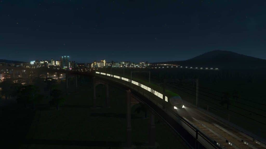 Cities: Skylines, tàu cao tốc di chuyển trên cầu vượt vào ban đêm, chiếu sáng đường ray.