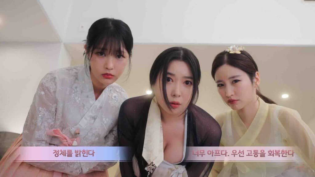 Ảnh gameplay Trilogy of the Moon: Eternal Rebirth, ba cô gái mặc trang phục Hanbok hiện đại đang ngồi trong một căn phòng. Hai cô gái bên cạnh đang lắng nghe cô gái ở giữa nói chuyện, với phụ đề tiếng Hàn bên dưới.