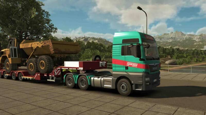 Trải nghiệm lái xe tải chở hàng nặng trong Heavy Cargo: chiếc xe đầu kéo màu xanh ngọc đang kéo rơ moóc chở một máy xúc lật khổng lồ màu vàng lên dốc. Khung cảnh đồi núi phía xa và thời tiết nắng đẹp tạo nên một chuyến đi đầy thử thách.