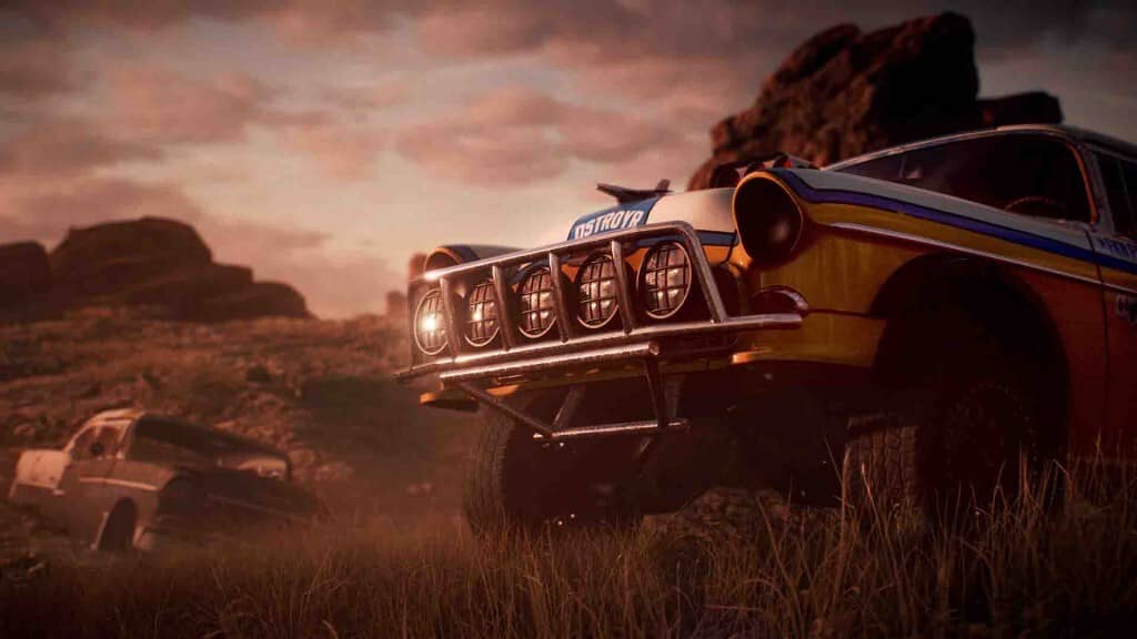 "Cảnh đua xe offroad trong Need for Speed Payback" "Ảnh gameplay Need for Speed Payback, một chiếc xe đua offroad kiểu cổ điển màu vàng cam đang dừng trên con đường đất ở sa mạc, phía sau là những tảng đá lớn và ánh hoàng hôn."