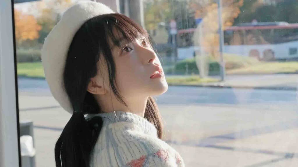 Love Begins With Goodbye: Nữ chính ngồi bên cửa sổ tàu điện, quay đầu mỉm cười.